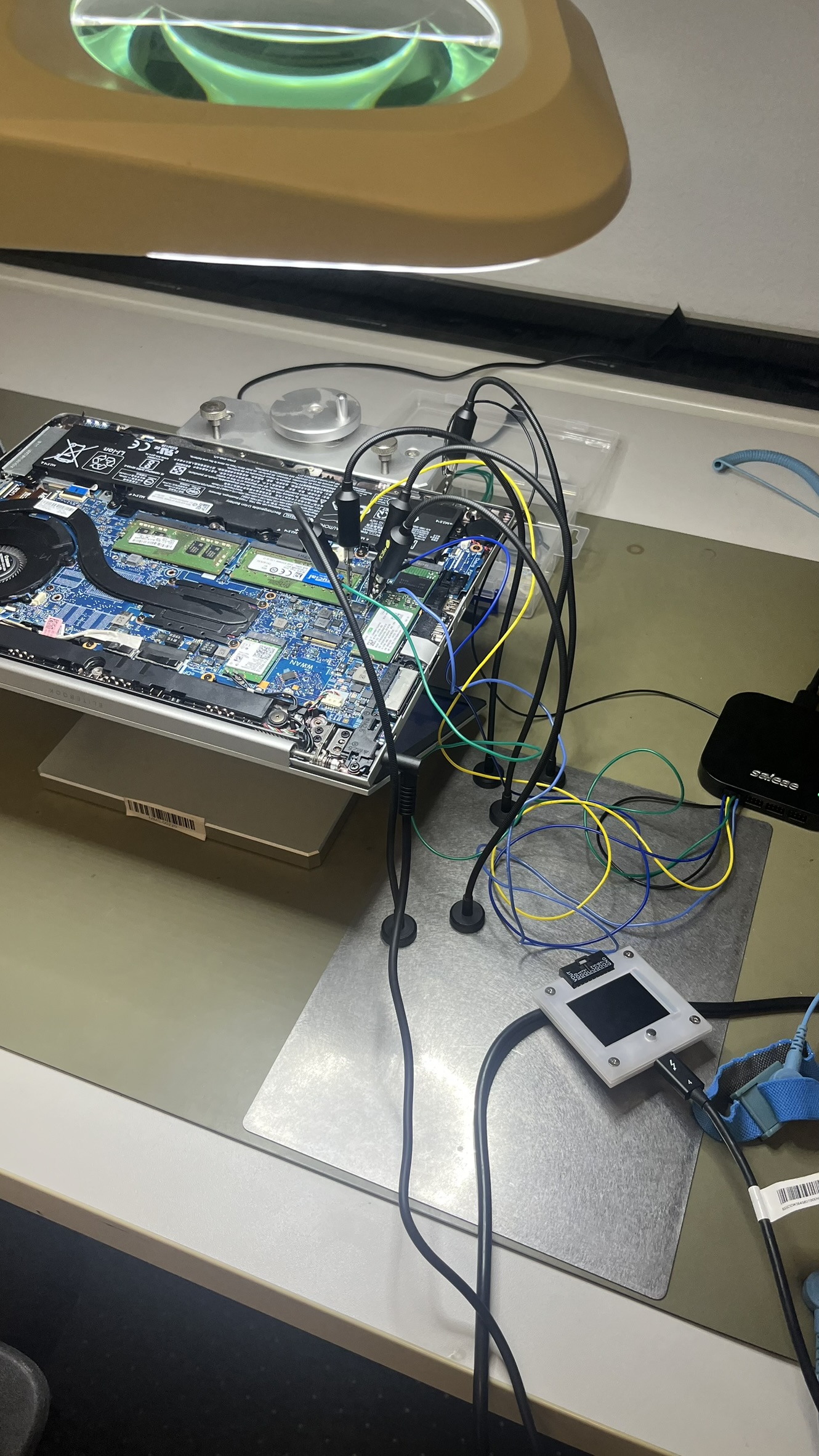 The same laptop motherboard with 5 logic probes attached to a chip